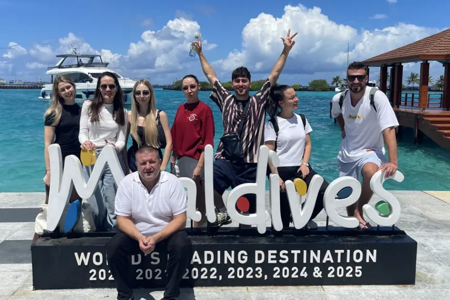 Группа падел-кэмпа No Drama Padel на Мальдивах у надписи Maldives