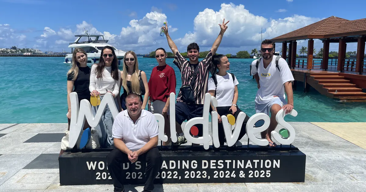 Группа падел-кэмпа No Drama Padel на Мальдивах у надписи Maldives