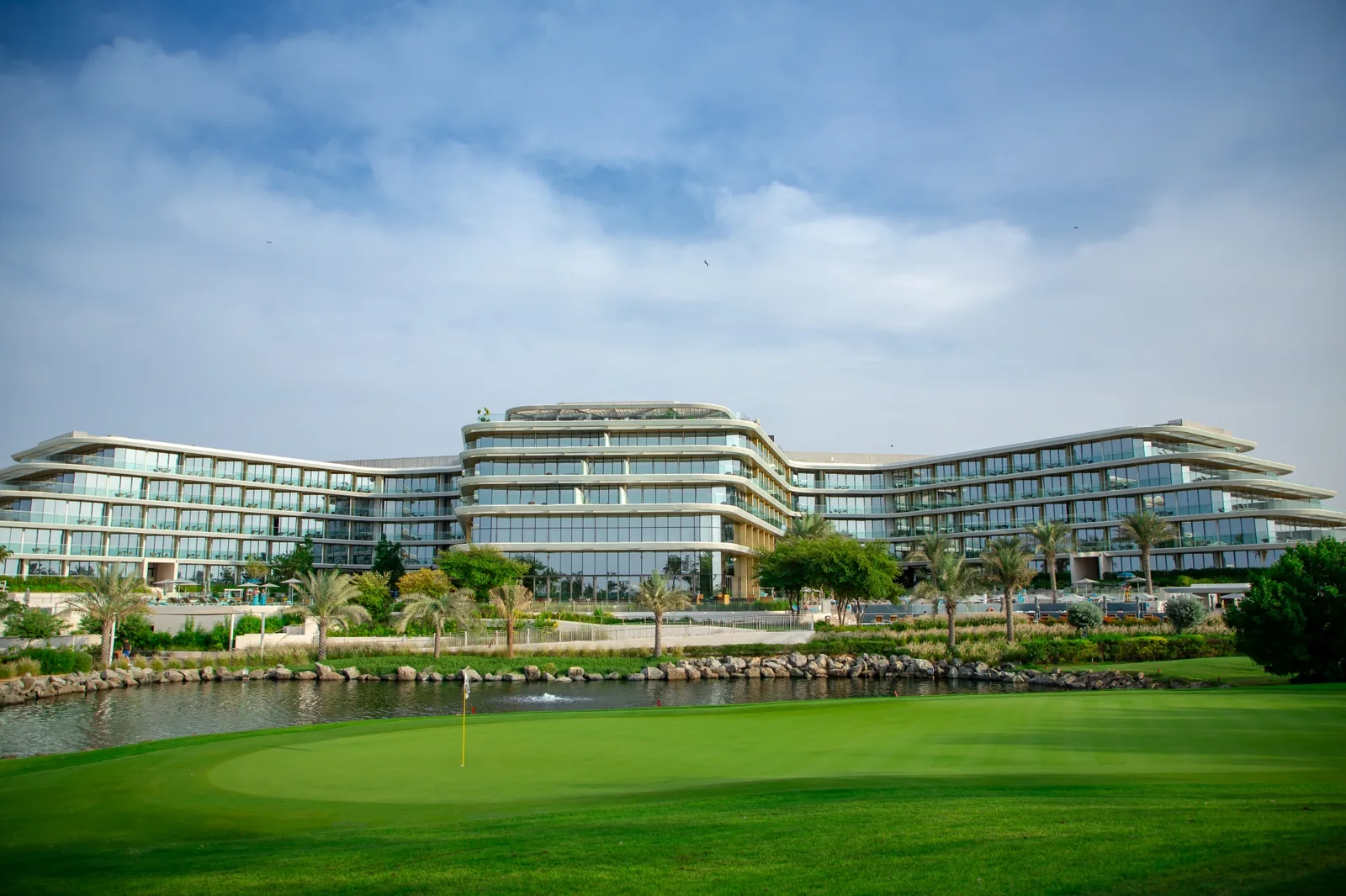 Дубай, JA Lake View Hotel: здание отеля у озера и зелёное поле